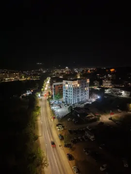 Pogled iz vazduha na osvijetljenu zgradu i okolne ulice noću. - image 4