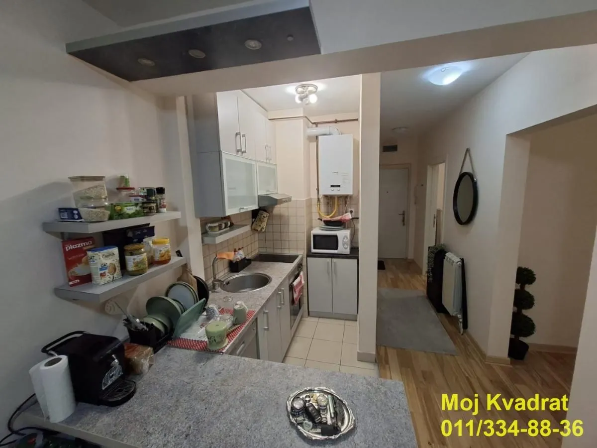 Manja kuhinja sa belim elementima i šankom.