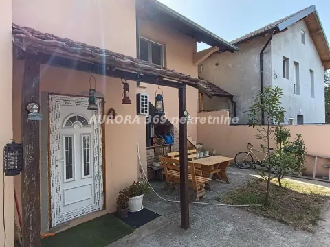 Pogled na dvorište i ulaz u kuću sa natkrivenom terasom i drvenim stolom. - image 3