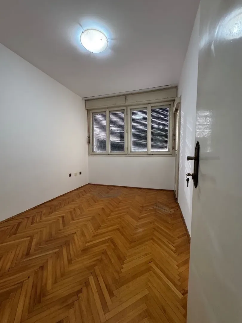 Prazna soba sa parketom i prozorom.