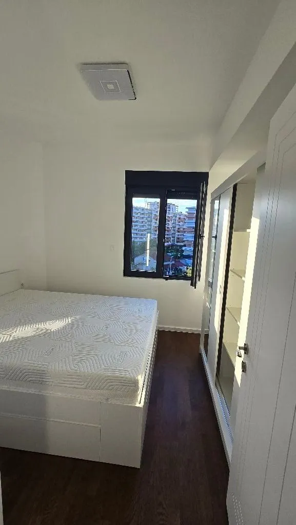 Bedroom with a double bed, white wardrobe, and a view through the window.
