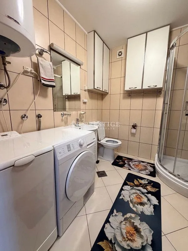 Small bathroom with a shower cabin, washing machine, and sanitary fixtures.