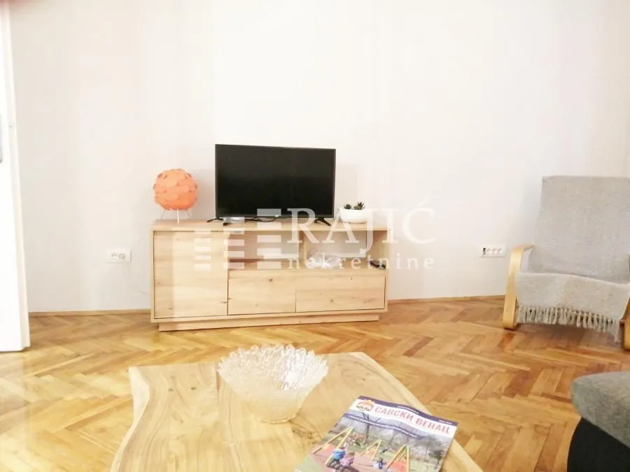 Living room with a TV cabinet and parquet flooring.