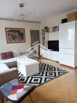 Living room with a sofa, TV, and white furniture units. - image 3