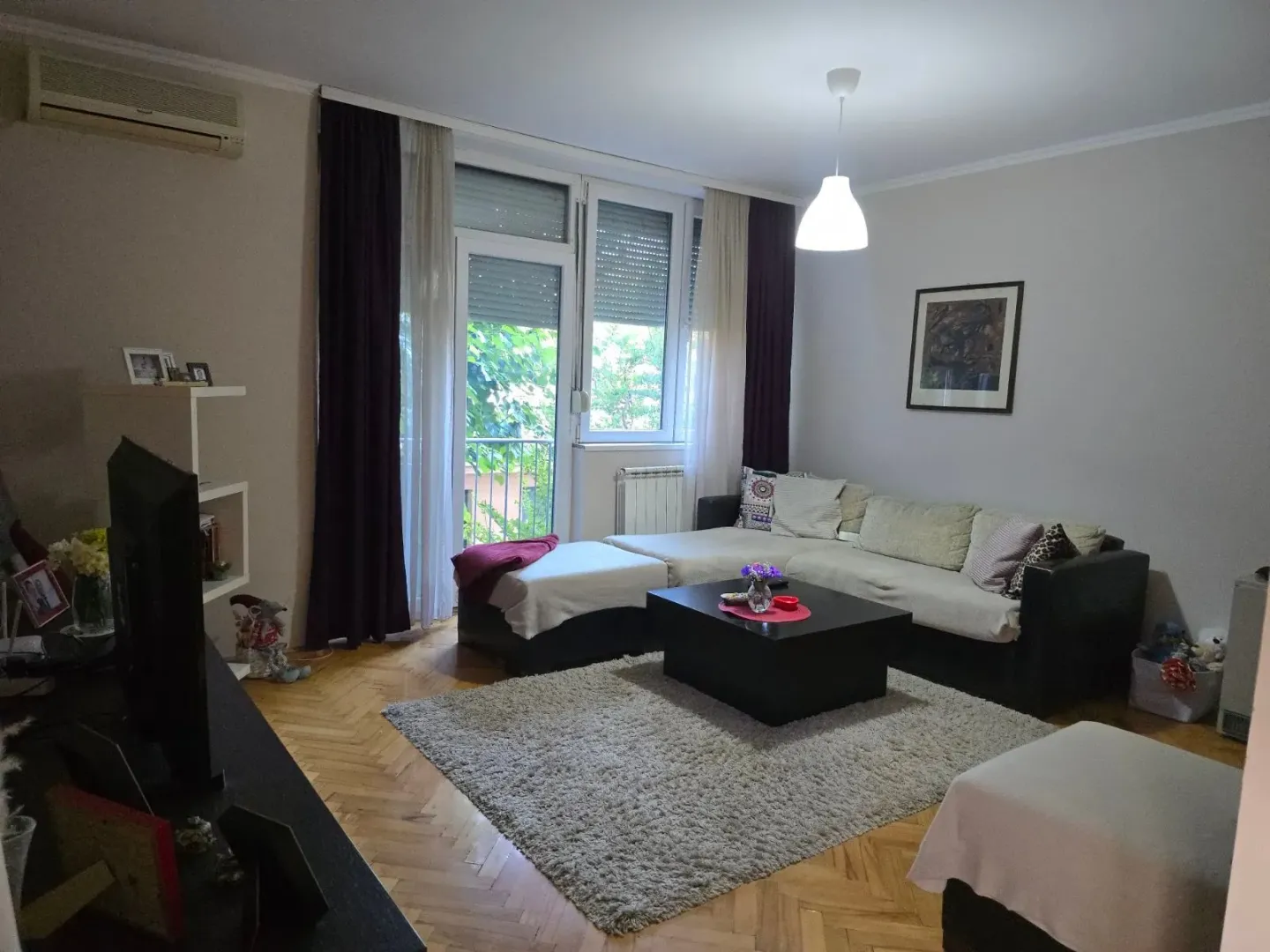 Uređena dnevna soba sa garniturom, stočićem i izlazom na terasu.