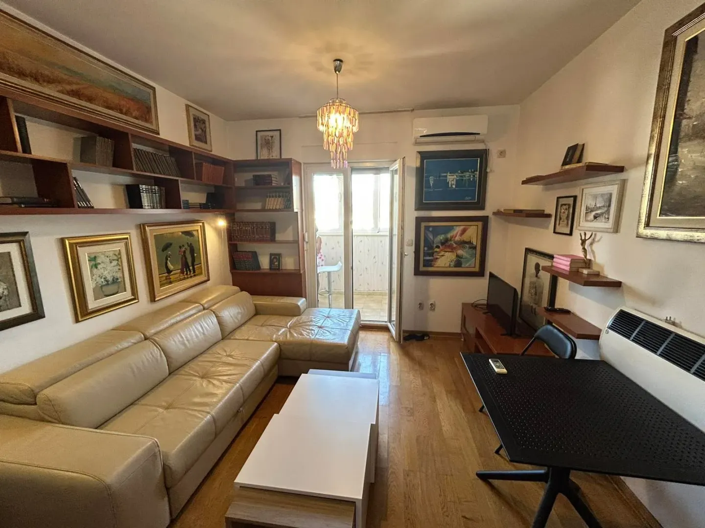 Living room furnished with a leather sofa, bookshelves and a dining table.