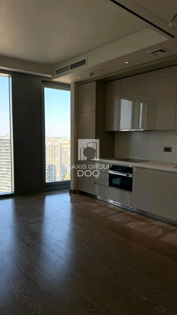 Modern kitchen with fitted units and a large window offering city views.