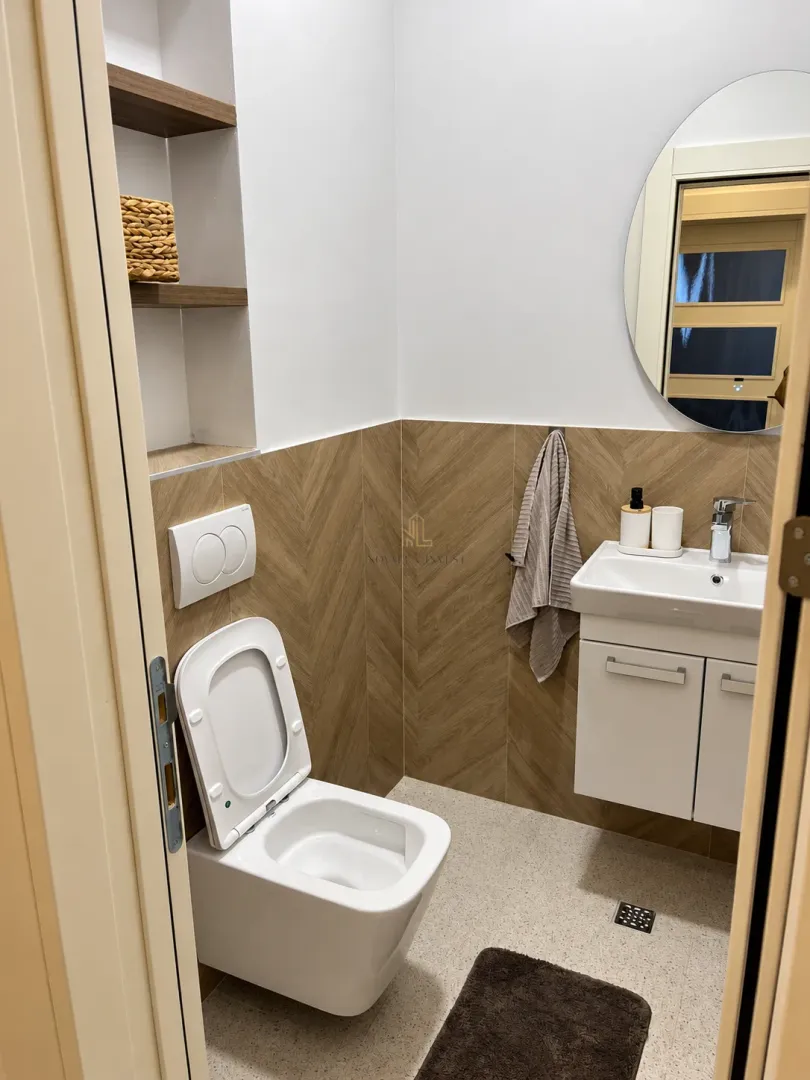 Small bathroom with a toilet, washbasin, and round mirror.