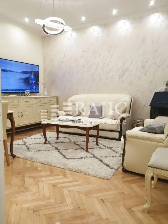 Living room furnished with a sofa set, TV cabinet, and parquet flooring.