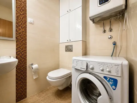 Small bathroom with washing machine, toilet, and built-in cabinet. - image 8