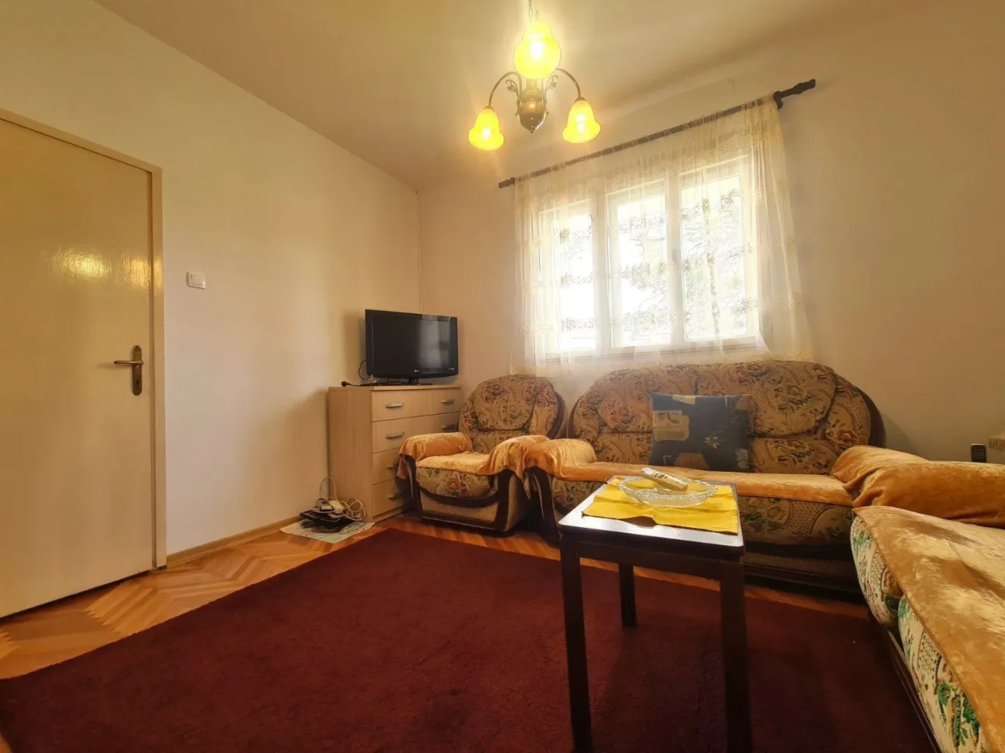 Simply furnished living room with a seating set and a TV.