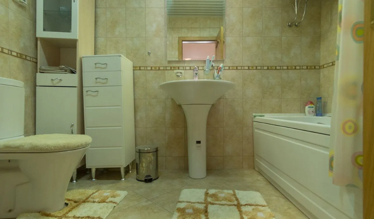 Kupatilo opremljeno umivaonikom, wc šoljom, kadom i kupatilskim namještajem.