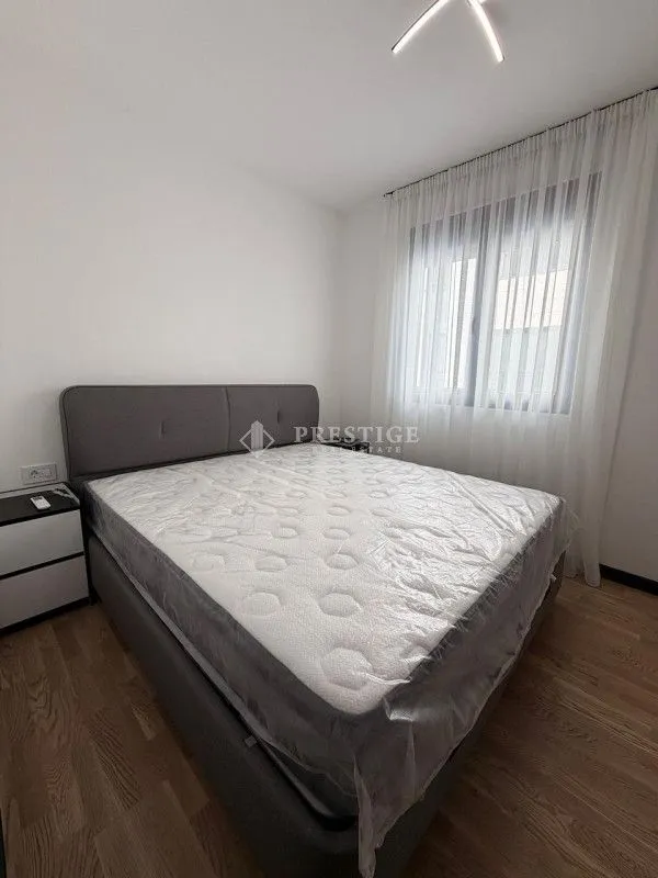 Moderna spavaća soba sa bračnim krevetom i bijelim zavjesama.