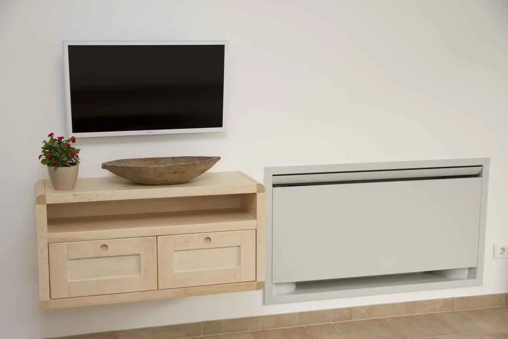 Zidni televizor iznad drvene komode i ugrađeni klima uređaj.