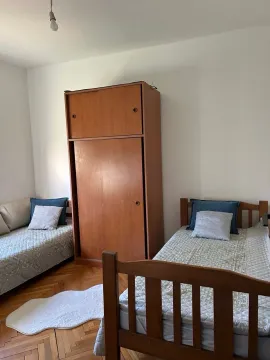 Furnished bedroom with two beds and a wooden wardrobe. - image 5