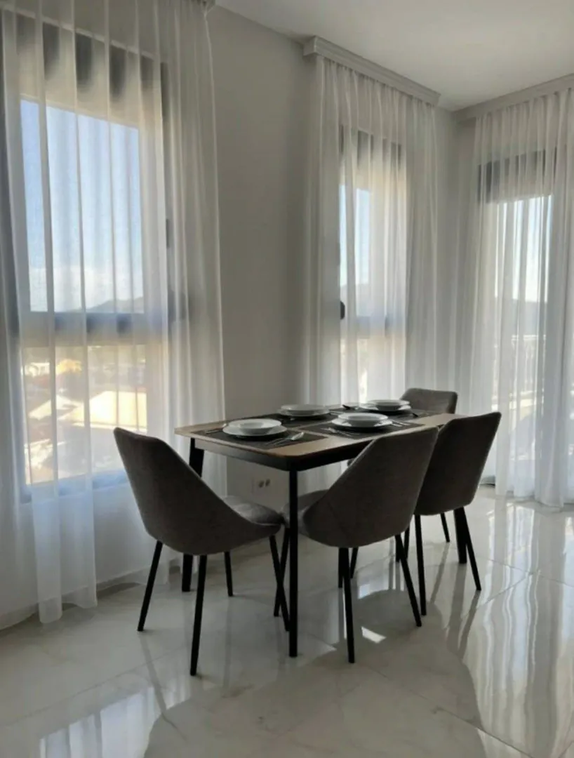 Dining area with a table, four chairs, and large windows.