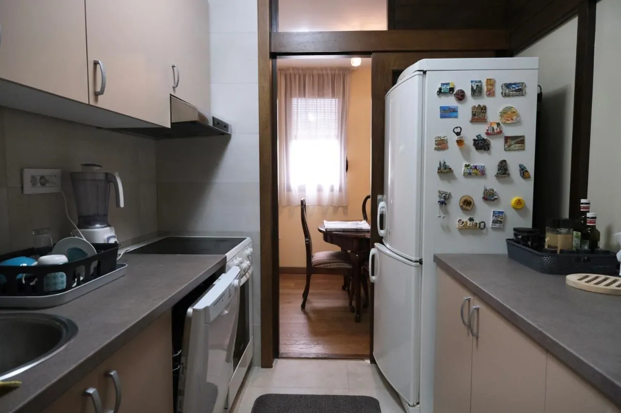 Practical kitchen with a white refrigerator and a view towards the dining area.