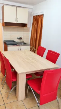 Trpezarija sa stolom, crvenim stolicama i manjom kuhinjskom nišom u pozadini. - image 6