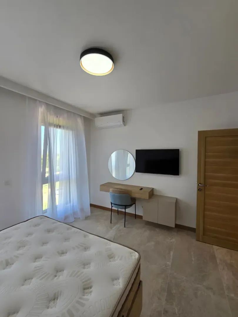Bedroom with a bed, desk, mirror, and wall-mounted television.