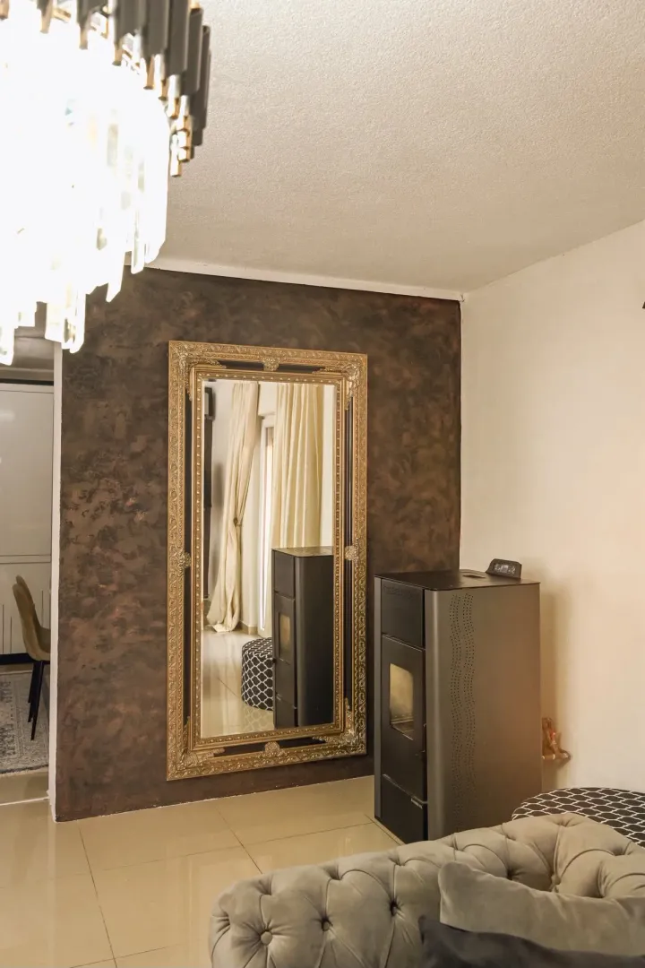Living room with sofa, pellet stove, and a large wall mirror.