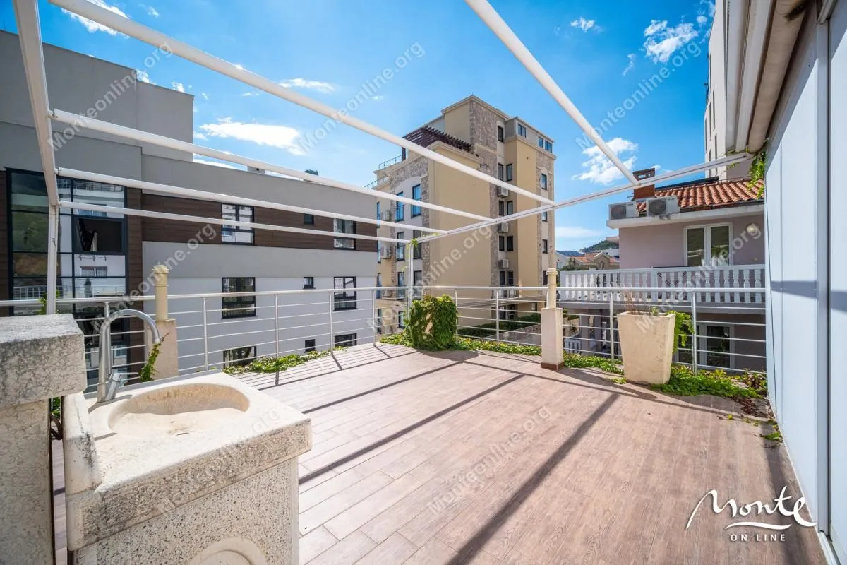 Spacious terrace with wooden flooring, a sink, and a metal structure.