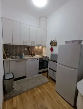 Small equipped kitchen with white cabinetry and appliances. - image 2