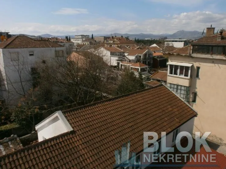 View from the window overlooking city rooftops and surrounding buildings.