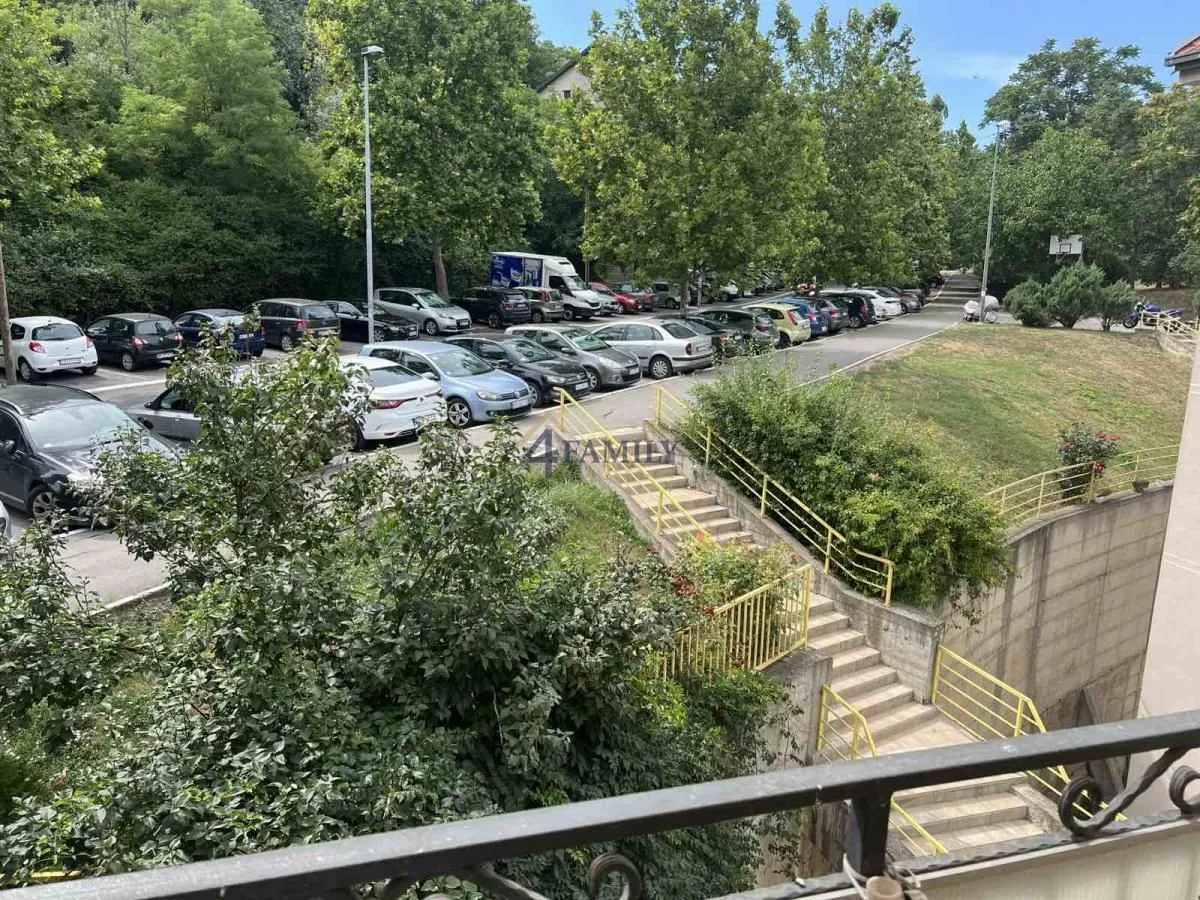 Pogled sa terase na parking i zelenu površinu ispred zgrade.