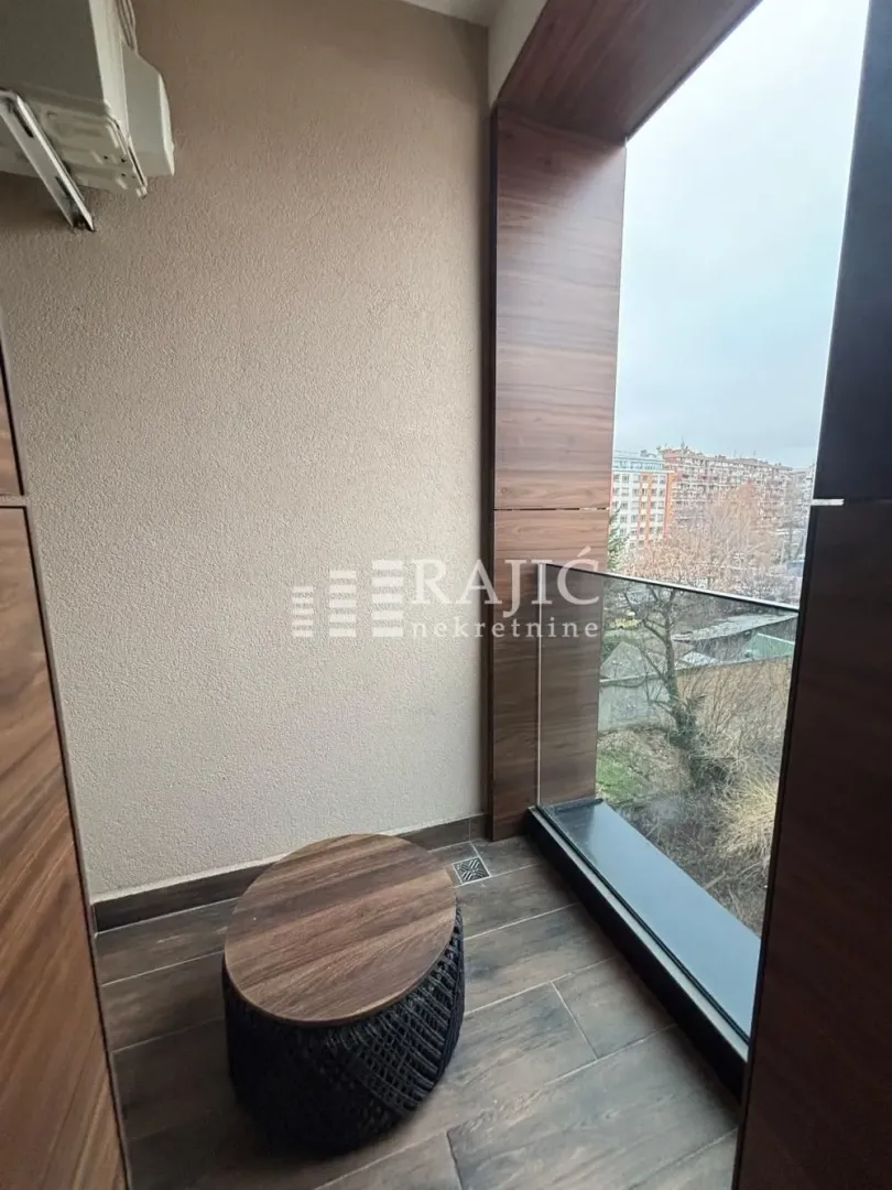 Small enclosed balcony with wooden wall panels and a low coffee table.