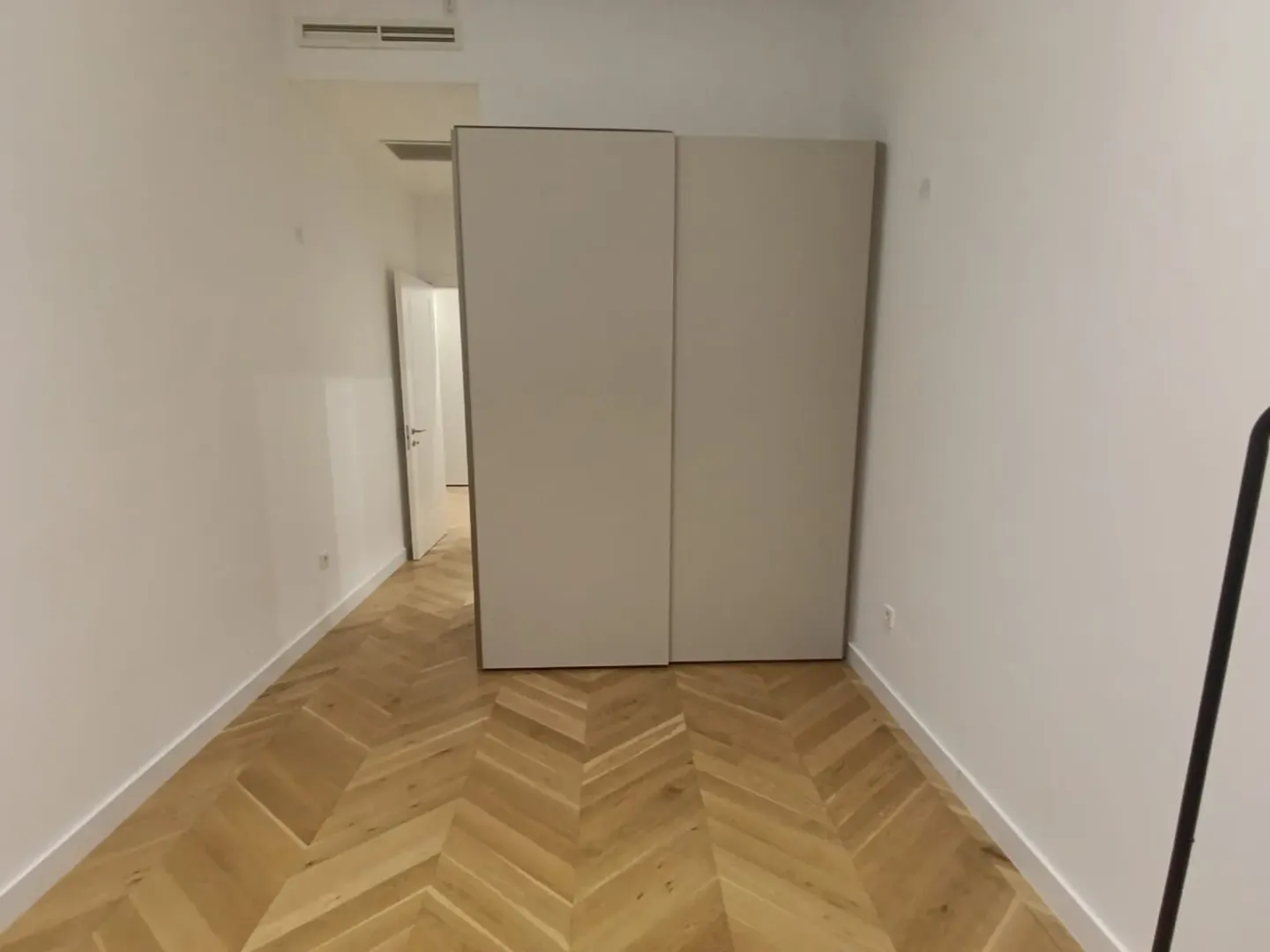 Spavaća soba sa ugradnim ormarom i parketom u riblju kost.