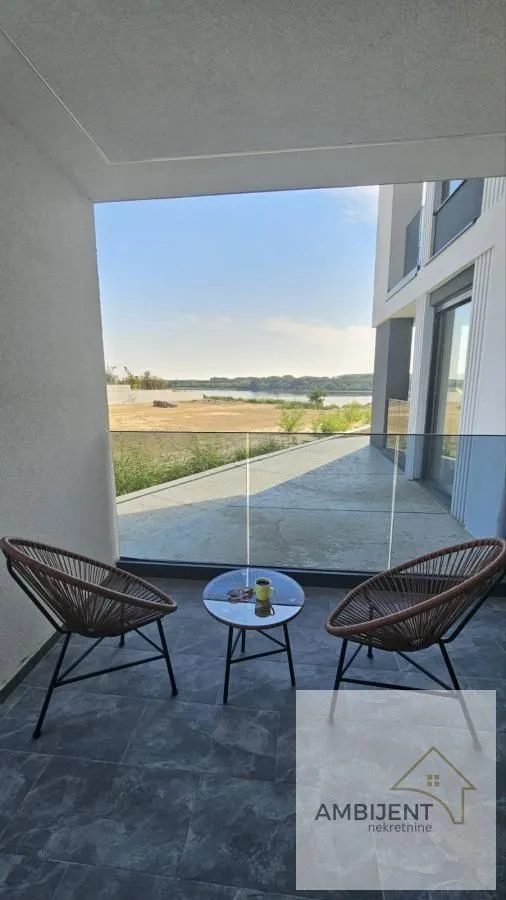Natkrivena terasa sa garniturom za sedenje i pogledom na reku.