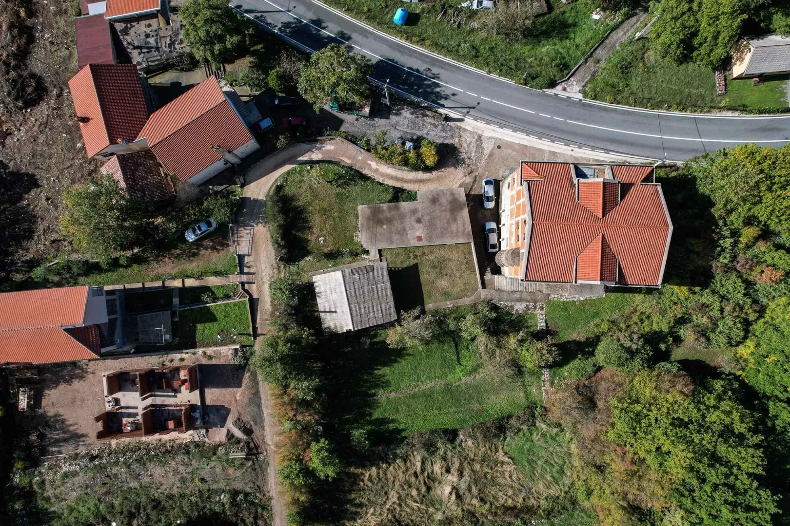 Pogled iz vazduha na kuću, okućnicu i okolno imanje sa putem.