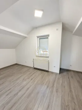 Prazna potkrovna prostorija sa belim zidovima, laminatom, prozorom i radijatorom. - image 6