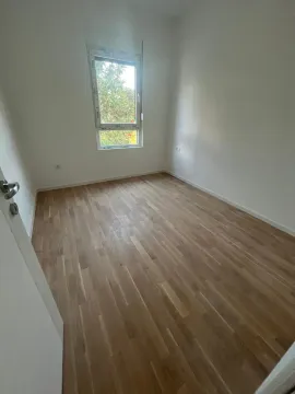 Prazna prostorija sa parketom i prozorom koji gleda na zelenilo. - image 4