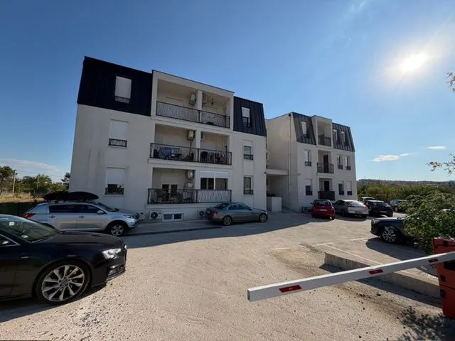 Eksterijer stambene zgrade sa parkingom i rampom.