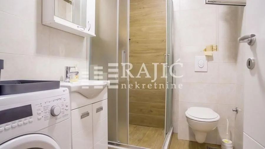 Modernly equipped bathroom with a shower cabin and washing machine.
