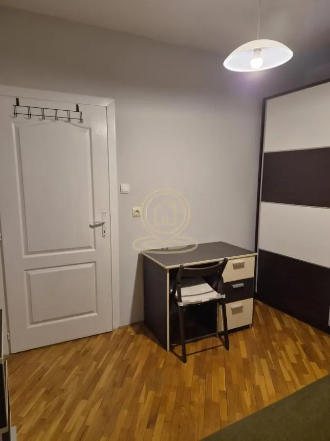 Manja spavaća soba sa radnim stolom, plakarom i drvenim podom.