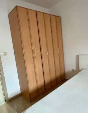 Pogled na drveni garderober i krevet u spavaćoj sobi. - image 7