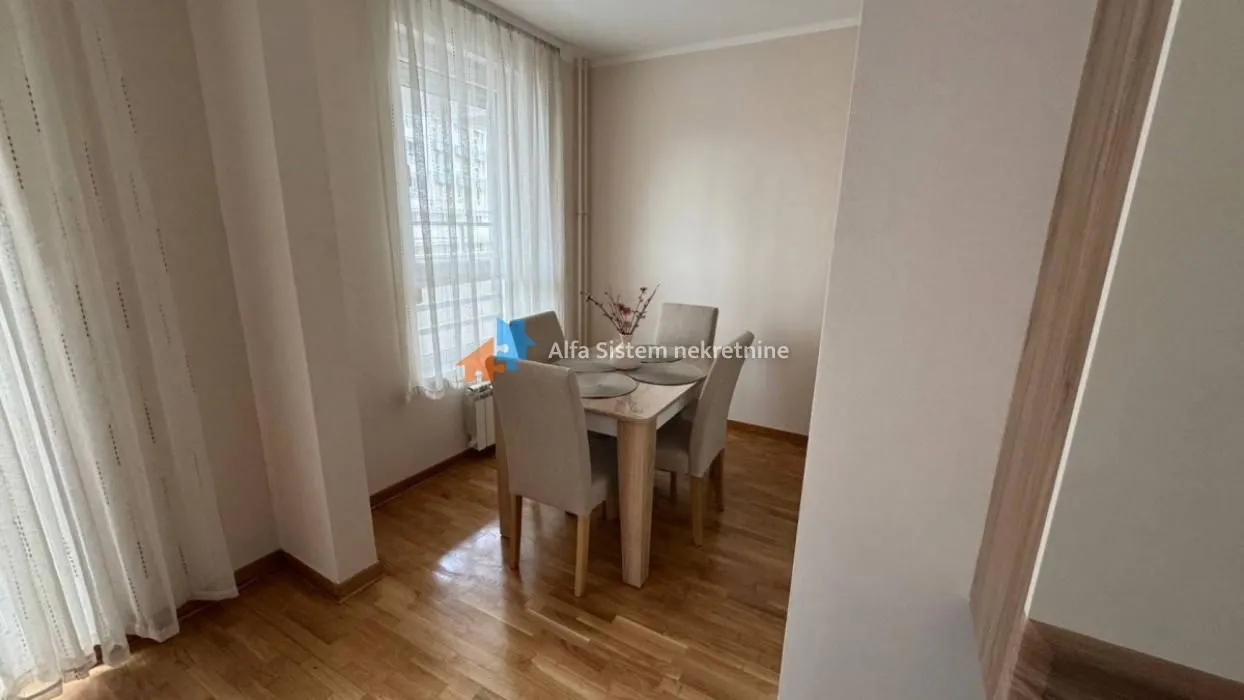Manja trpezarija sa stolom i stolicama pored prozora.