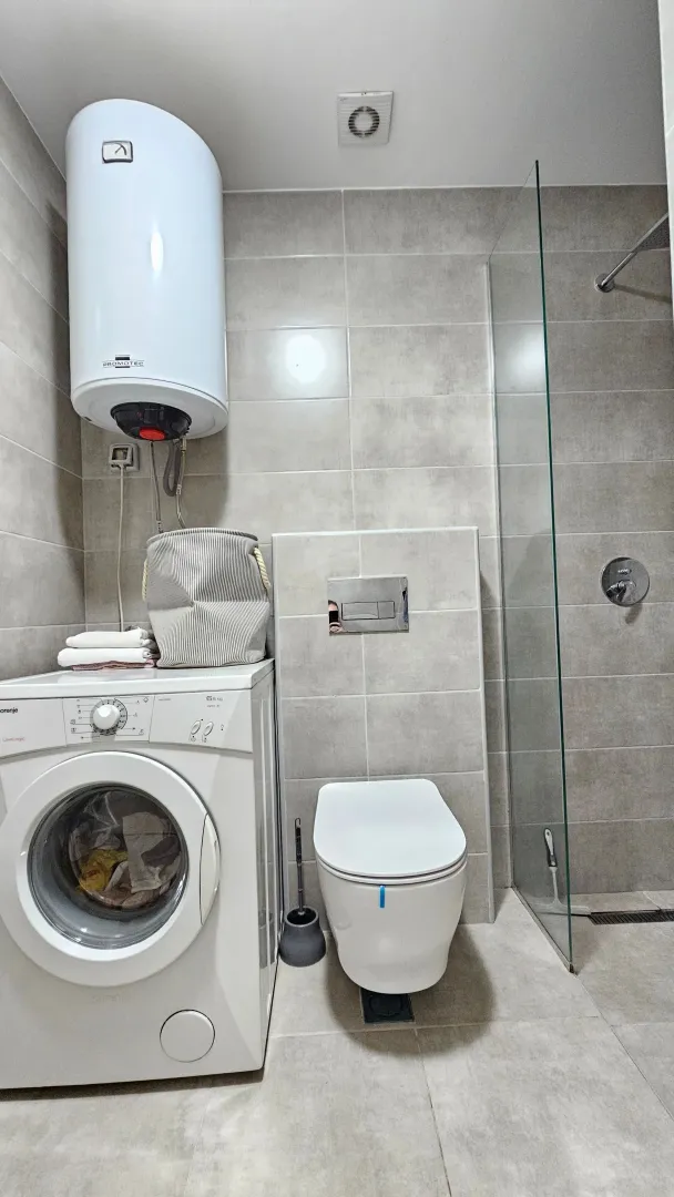 Modernly equipped bathroom with a walk-in shower, washing machine, and water heater.