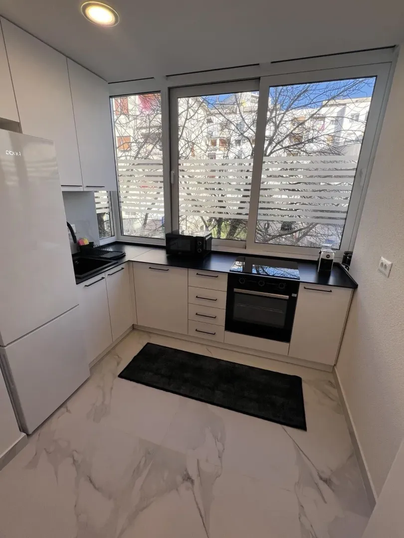 Bright and modern kitchen with white cabinets and built-in appliances.