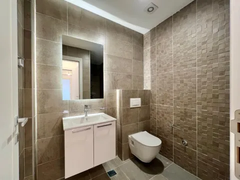 Moderne kupatilo sa umivaonikom, ogledalom i toaletom obloženo keramičkim pločicama u zemljanim tonovima. - image 5