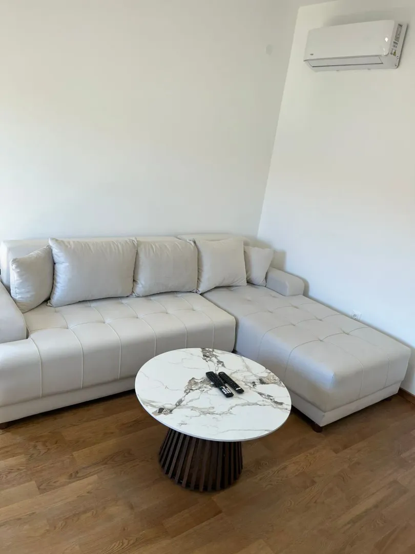 Dnevna soba sa bijelom ugaonom garniturom i okruglim stočićem.