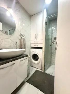 Savremeno opremljeno kupatilo sa tuš kabinom, umivaonikom i ugrađenom mašinom za veš. - image 12