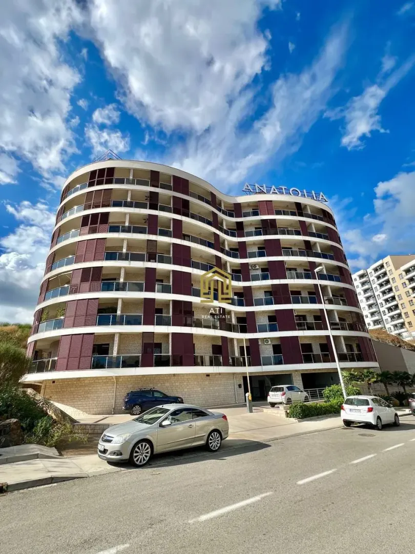 Exterior of a modern multi-family residential building with balconies and parking.