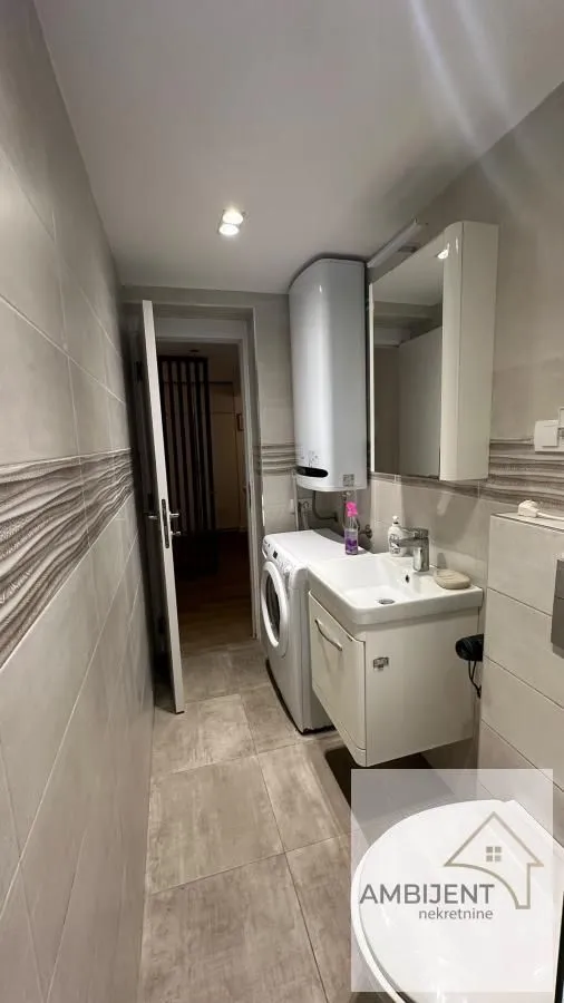 Small bathroom with a sink, washing machine, water heater, and toilet.
