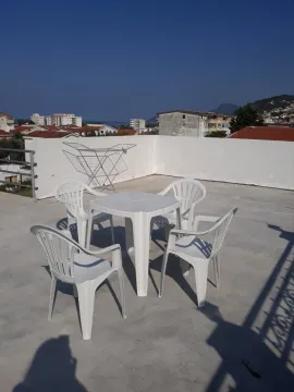 Rooftop terrace with white plastic table and chairs and surrounding view. - image 5