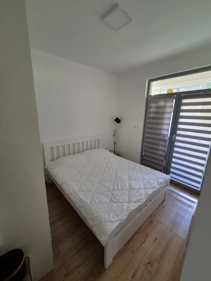 Svijetla spavaća soba sa bijelim krevetom i izlazom na terasu.