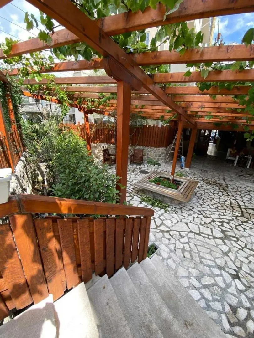 Yard with a wooden pergola and paved floor.