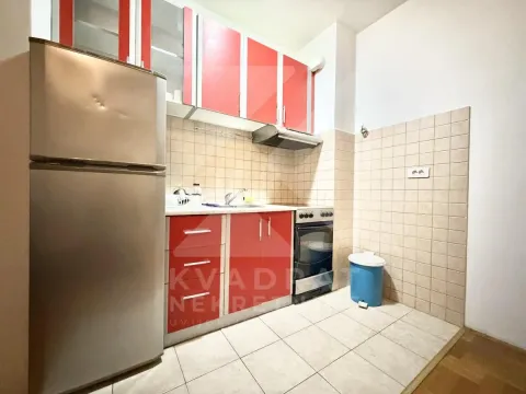 Kuhinja opremljena elementima jarko crvene boje, frižiderom i šporetom. - image 4